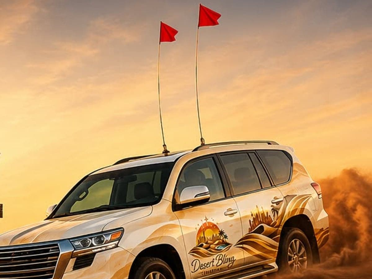 A Desert Bling 4x4 in desert livery throwing up sand on a dune drive at sunset